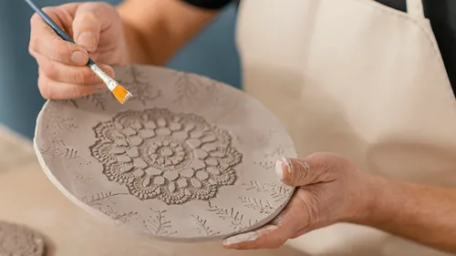 Person painting a textured clay plate.