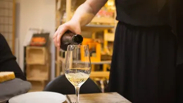 Person pouring wine into a glass.
