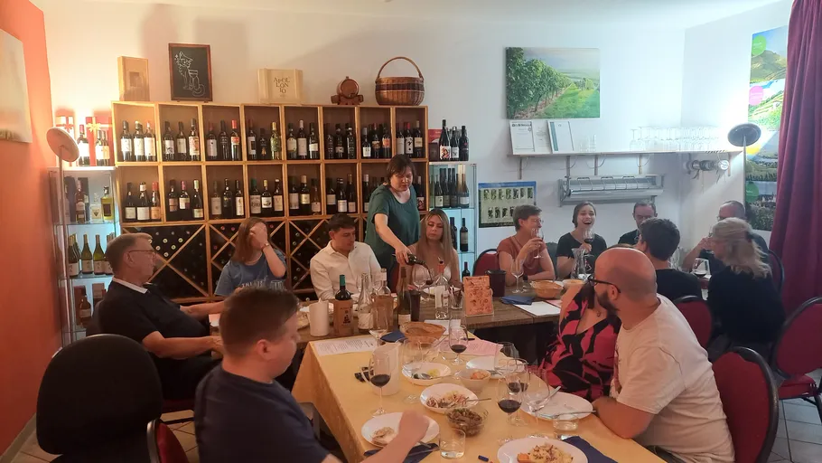Group gathered around tables in a wine cellar.