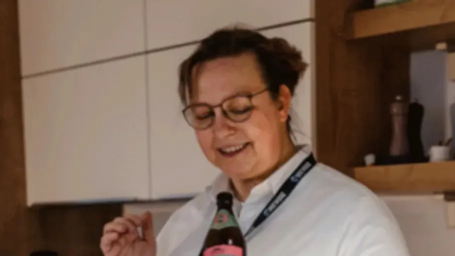 Person smiling while holding bottle in kitchen.