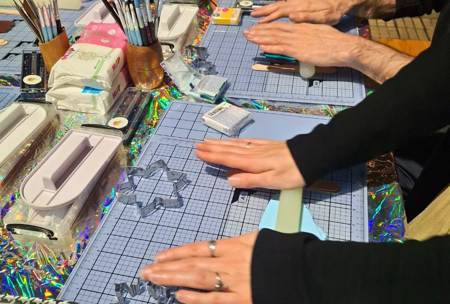 Hands crafting with tools on holographic table.