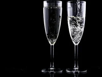 Two glasses of sparkling drink against a black background.
