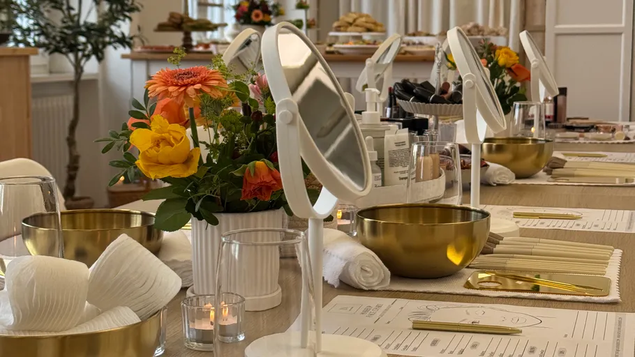 Kosmetikspiegel und Blumen auf einem Tisch.