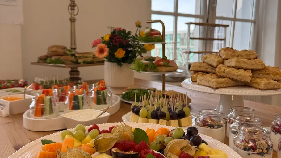 Verschiedene Buffets mit Obst und Gebäck im Raum.