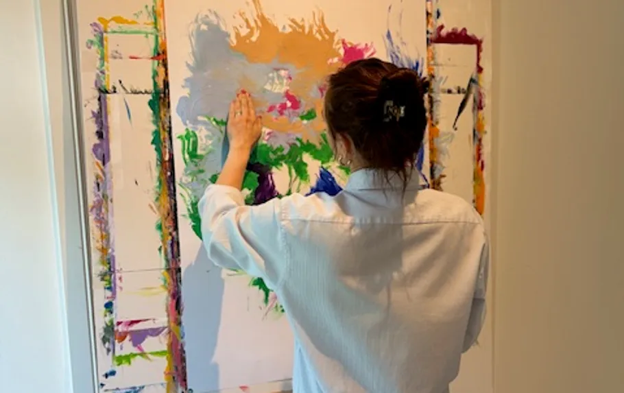 Person malt farbenfrohe abstrakte Kunst auf Leinwand.