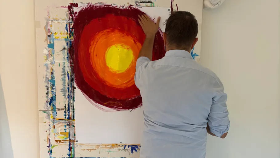 Man painting colorful abstract circle on canvas.