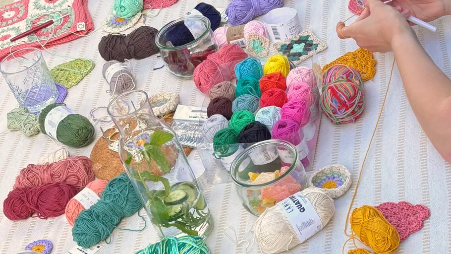 Hands crocheting amidst colorful yarns on table.
