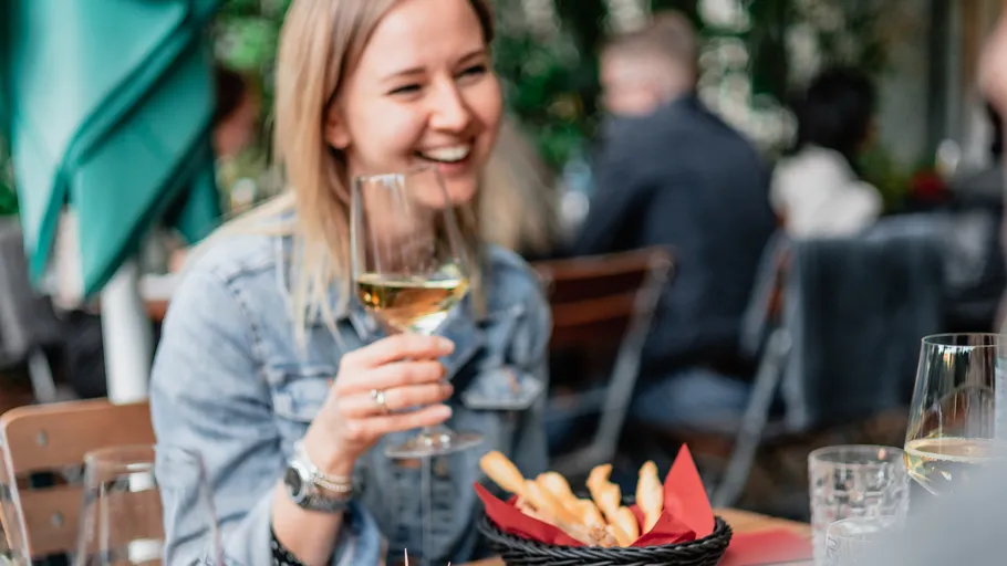 Woman holding wine glass in outdoor restaurant.