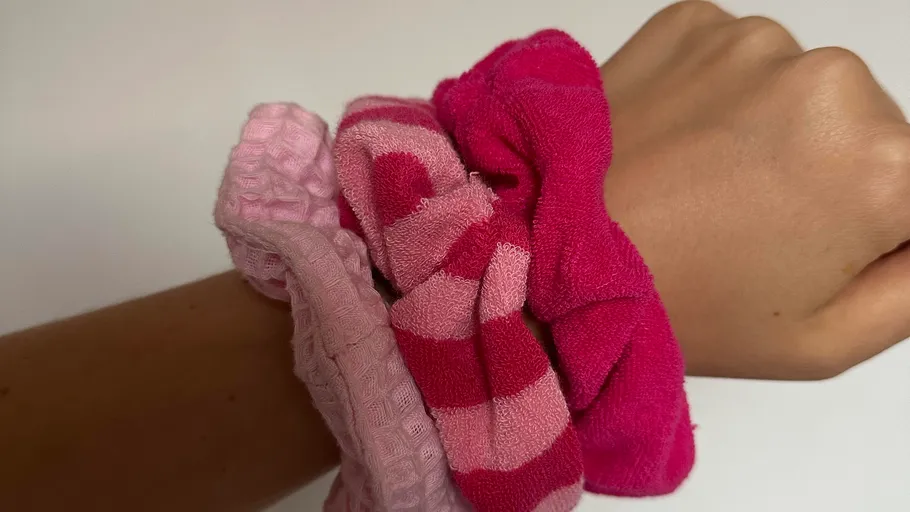 Wrist with three pink scrunchies on arm.