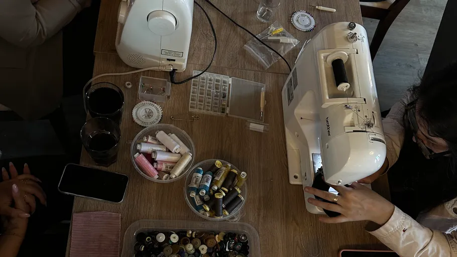 Person using sewing machine on wooden table.