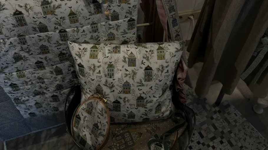 Decorative pillow with house pattern on chair.