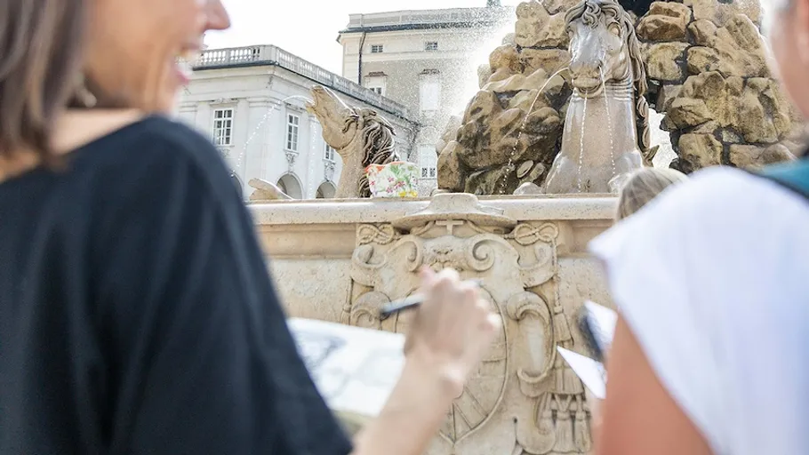 Menschen zeichnen nahe einem dekorativen Brunnen.