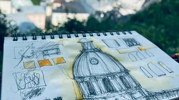 Sketchbook with architectural dome drawing outdoors.