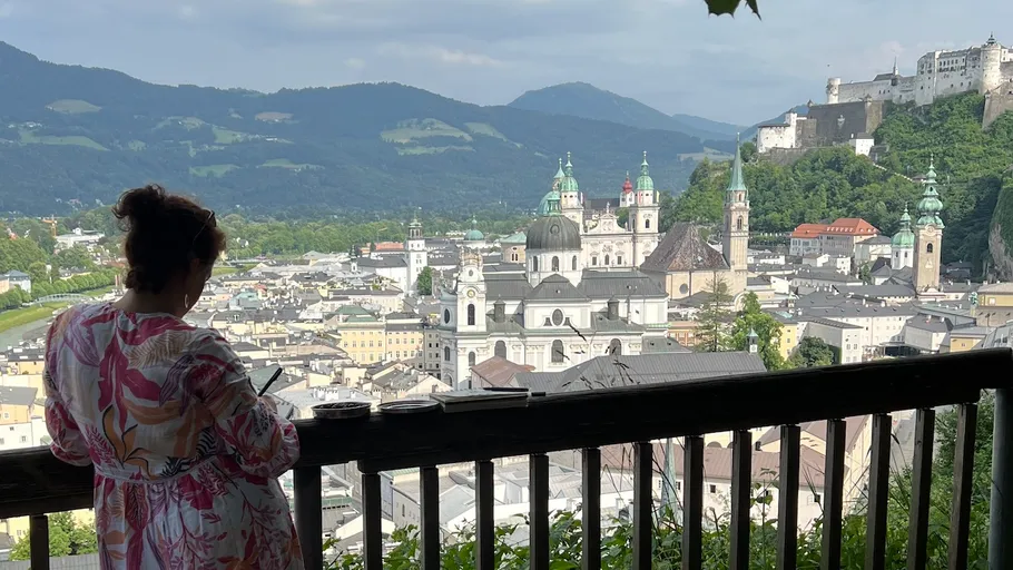 Woman painting cityscape from hilltop viewpoint.