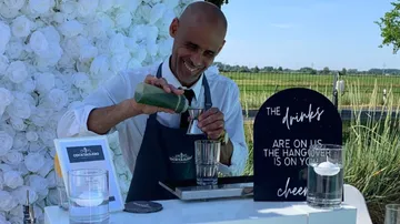 Man pouring drink at an outdoor bar station.
