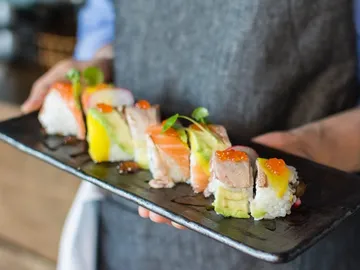 A plate of sushi is held by one person.