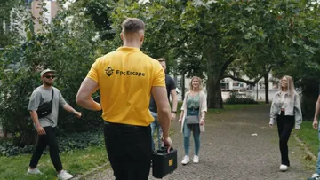 Man in yellow shirt leads a group outdoors.