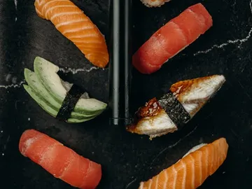 Sushi is on a black plate, ready to eat.