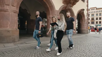 Gruppe geht unter Steinbögen in Stadt.