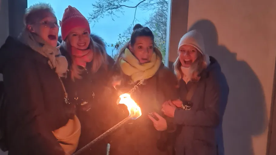 Vier Personen reagieren auf eine Fackel drinnen.