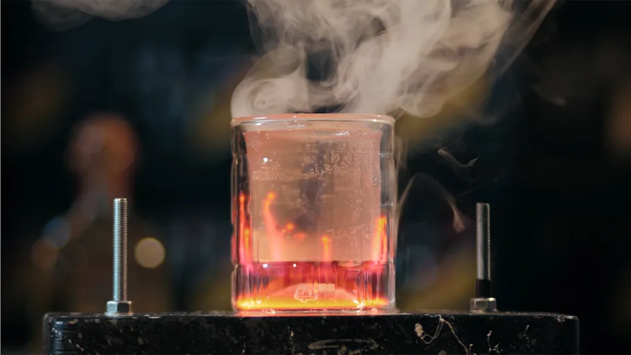 Glasbecher stößt Dampf auf dunklem Hintergrund aus.