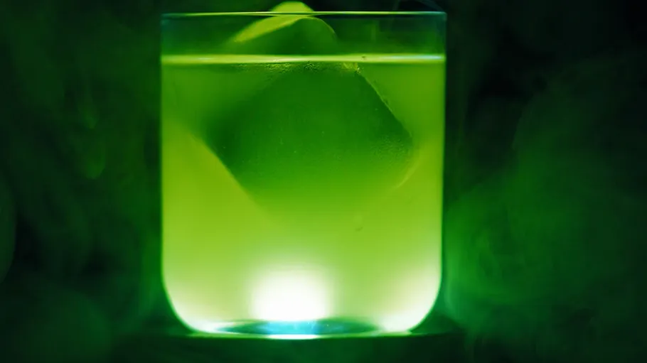 Leuchtendes grünes Getränk mit Eiswürfel.