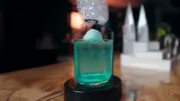 Blauer Cocktail mit einer großen Eiskugel.