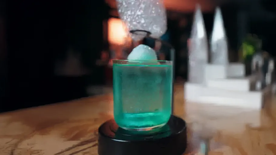 Blauer Cocktail mit einer großen Eiskugel.