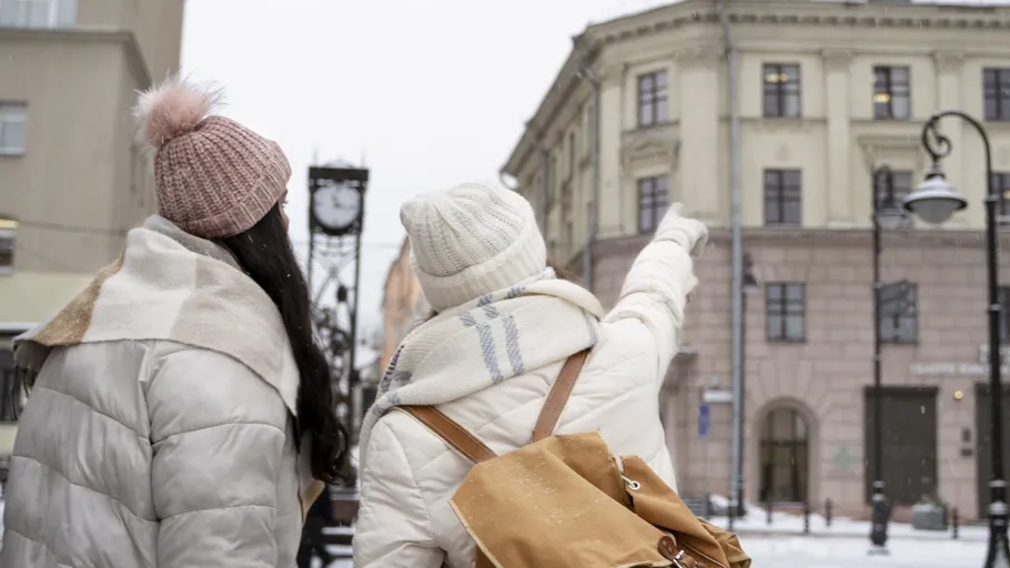 Two people pointing at historic building, snowy street.