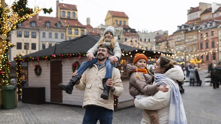 Family enjoying holiday market with festive lights.