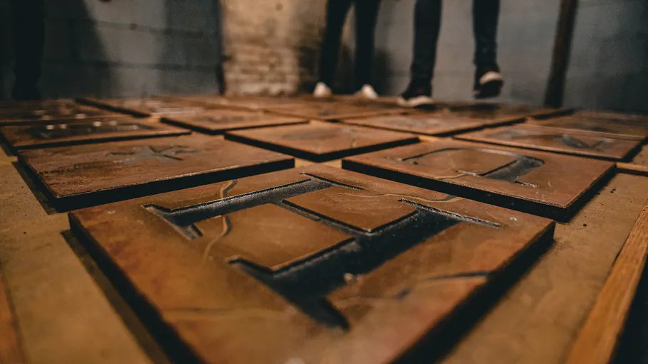 Große Buchstabenkacheln auf dem Boden, Beine sichtbar.