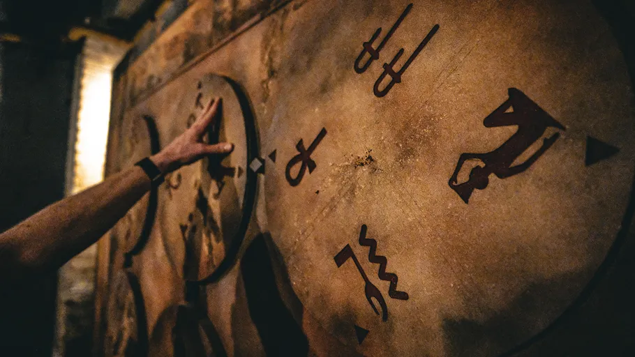 Person berührt Symbole an antik aussehender Wand.