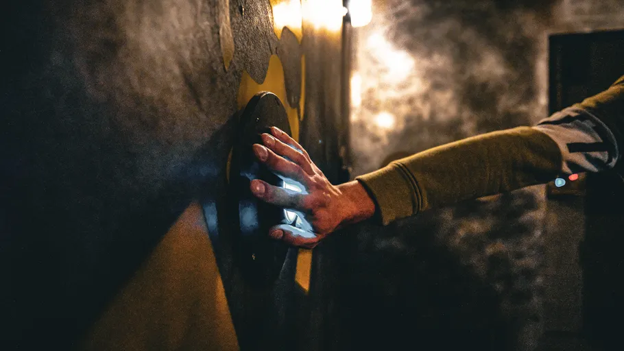 Hand drückt Knopf an einer dunklen Wand.