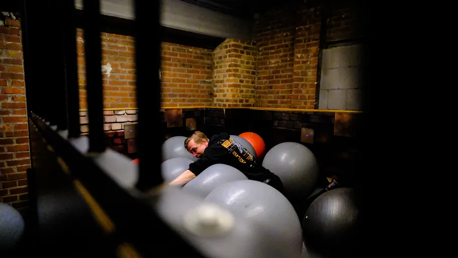 Person lying on exercise balls in a brick room.