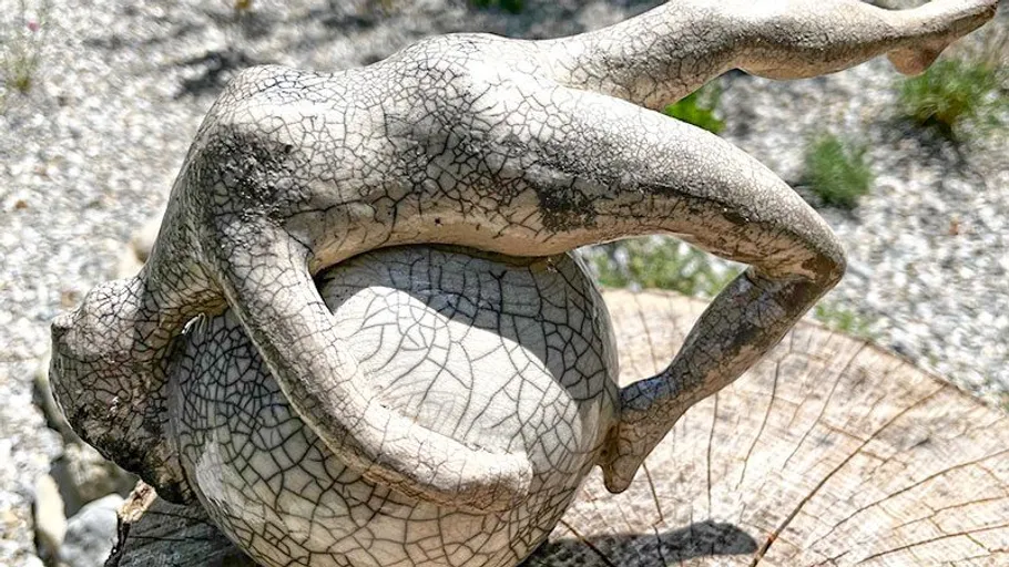 Sculpture of person on sphere outside.