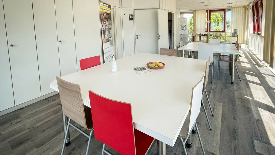 Leere Kantine mit Tischen und Stühlen.