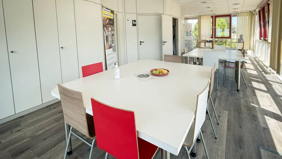 Meeting room with white tables, red chairs.