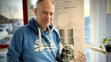 Man holding a sculpture in a room.