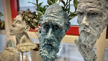Three expressive sculptures displayed in a gallery.