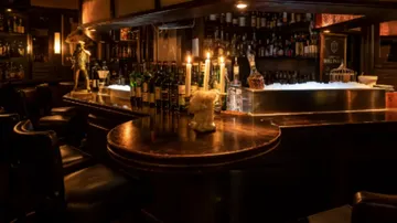 Schummrig beleuchtete Bar mit Kerzen und Flaschen.