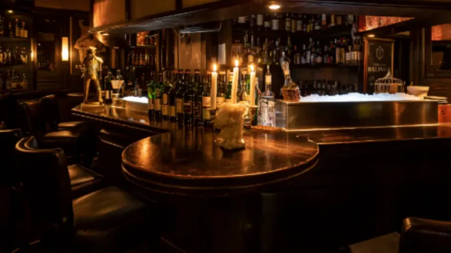 Dimly lit bar with candles and bottles.