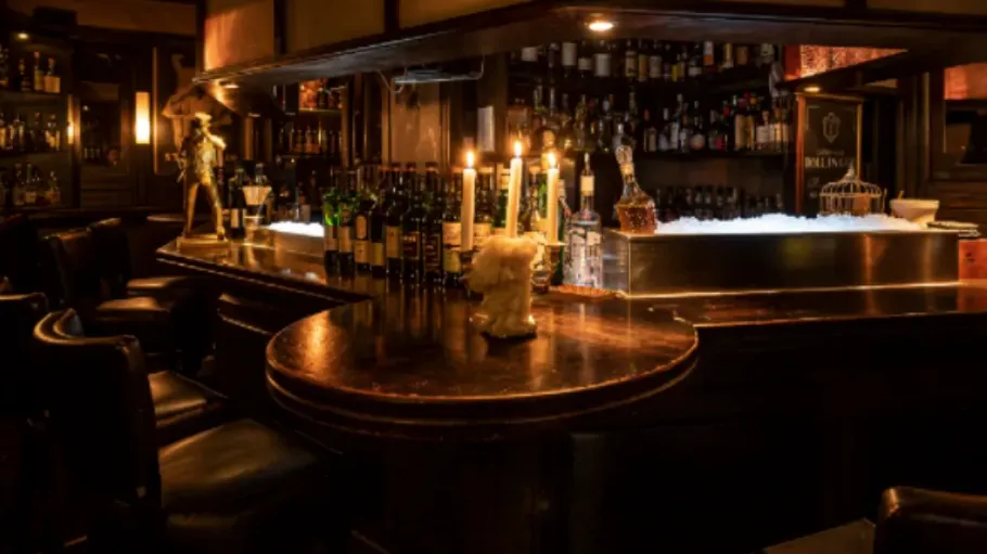Schummrig beleuchtete Bar mit Kerzen und Flaschen.