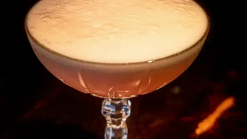 Schaumiger Cocktail in einem Stielglas.