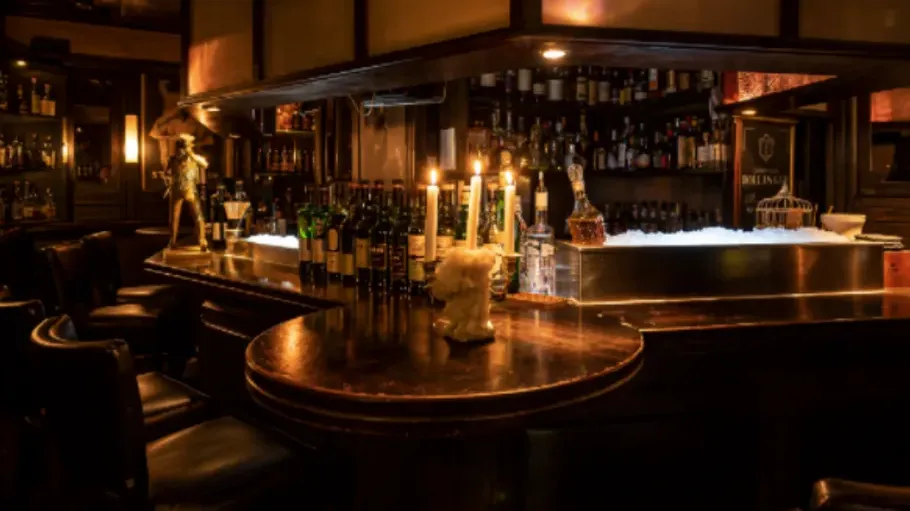 Candlelit bar with bottles in dim lighting.