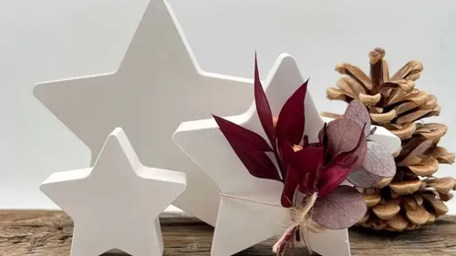 White stars and pinecone on wooden table.