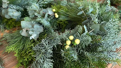 Green wreath with leaves and yellow berries.