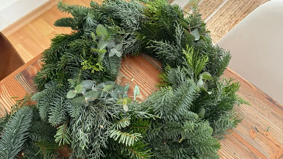 Grüner Kranz auf einem Holztisch.