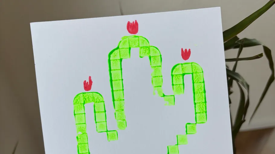 Green block cactus with red flowers on paper.