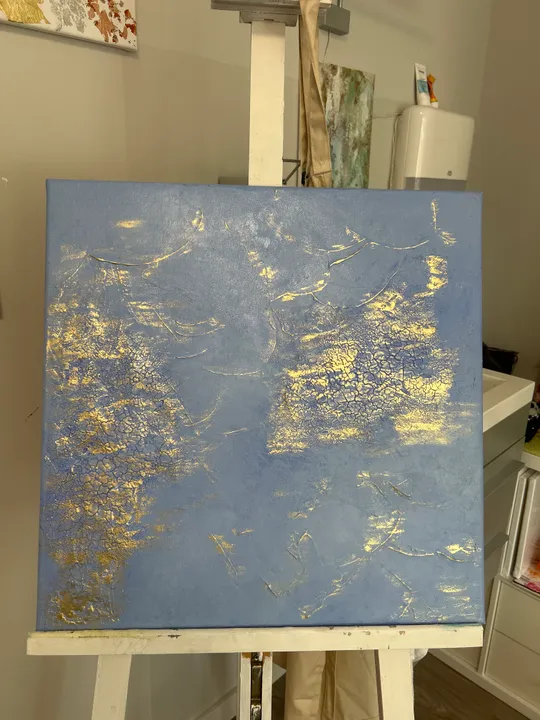 Blaue Leinwand mit goldenen Texturen auf Staffelei.