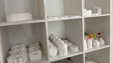 Weiße Keramikobjekte auf Regalen ausgestellt.